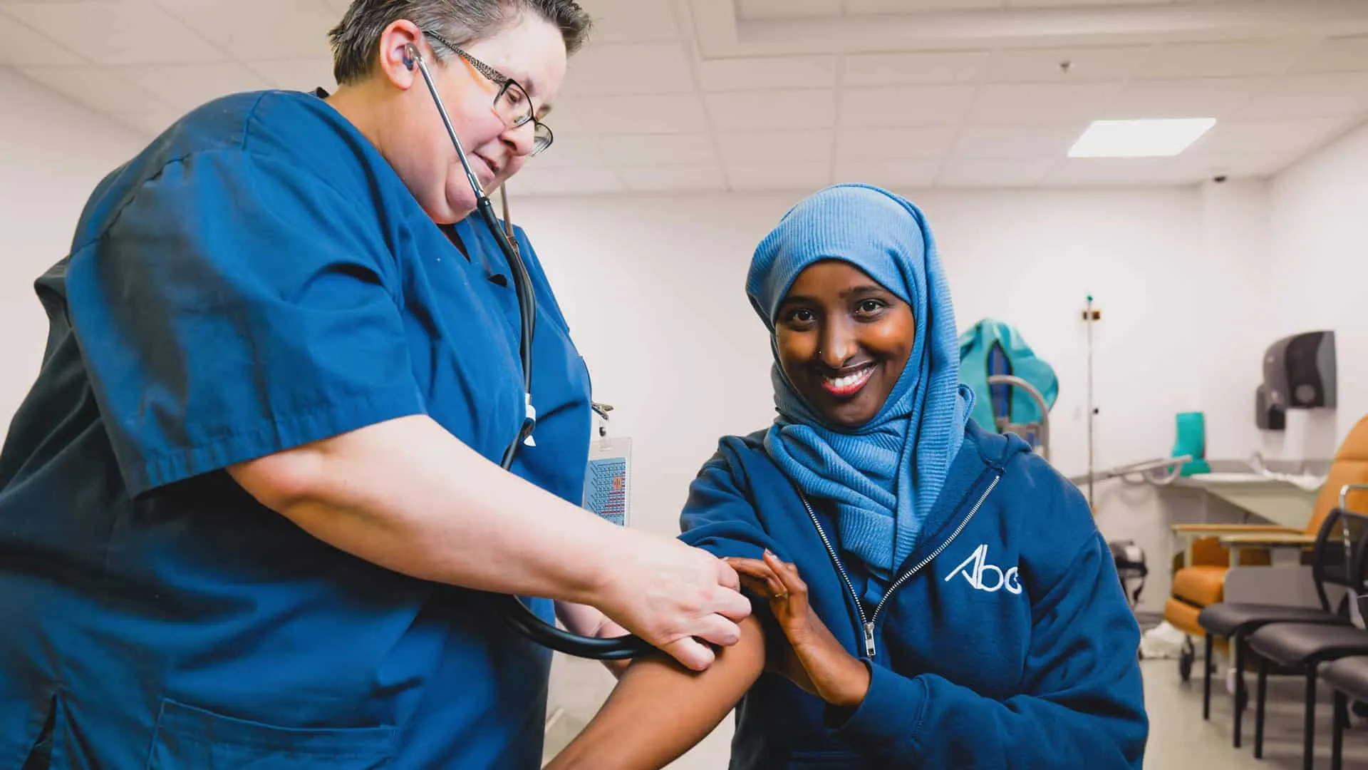 An ABES instructor in a skills lab teaching a student to take a blood pressure reading
