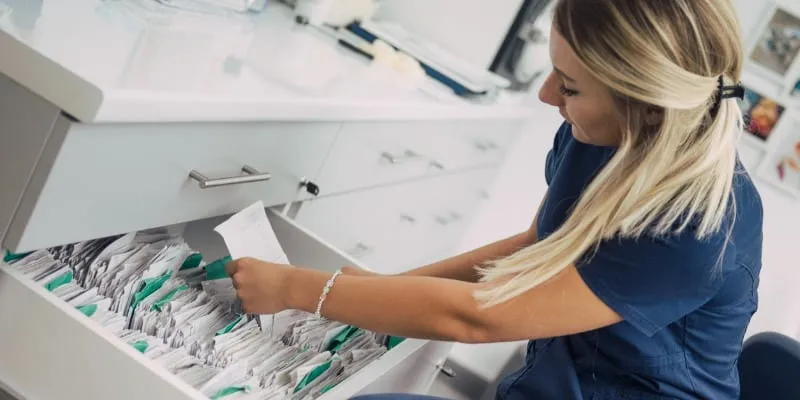 Young medical assisstant putting away files in doctors office